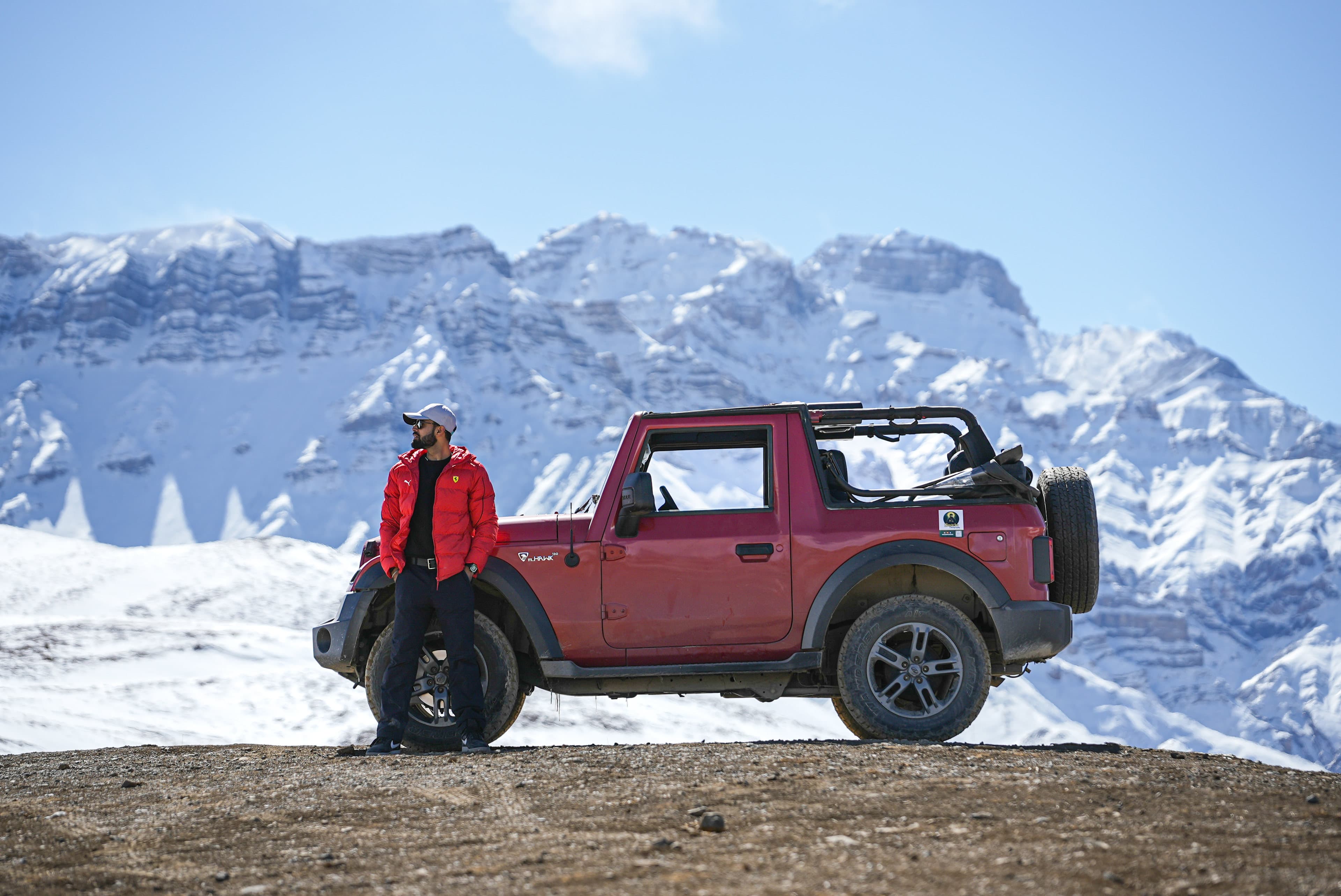 Yogi and his Thar on a ridge road under snow peaks